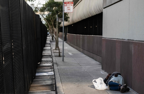 한 노숙자가 13일 아시아태평양경제협력체(APEC) 회의가 열리는 미국 샌프란시스코 정상회담장인 모스코니센터 주변의 안전 펜스 근처에서 잠을 자고 있다.  샌프란시스코 AFP 연합뉴스