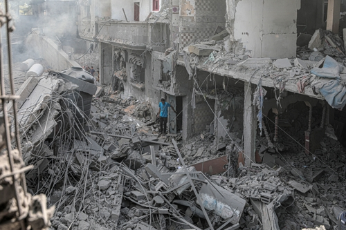 팔레스타인 무장 정파 하마스와 이스라엘 간 무력 충돌이 계속되는 가운데 13일(현지시간) 가자지구 부레이지 난민촌에서 한 주민이 이스라엘 공습으로 무너진 건물 잔해 가운데 서 있다. 가자지구 신화 연합뉴스