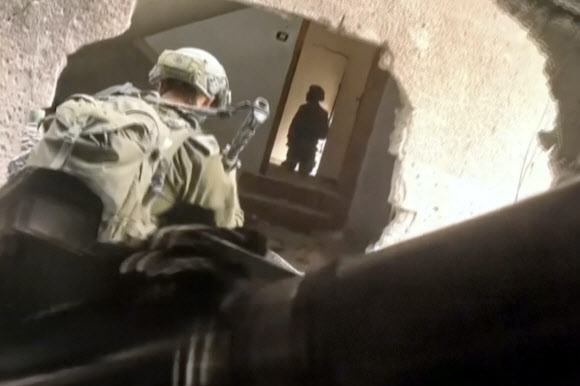 이스라엘방위군(IDF) 병사들이 팔레스타인 가자지구의 한 건물에 뚫린 구멍을  통해 들어가려 하고 있다. IDF가 16일(현지시간) 배포한 동영상을 캡처한 것이다. AP 연합뉴스