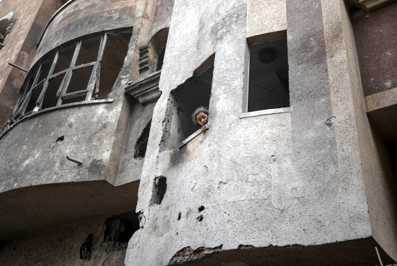20일(현지시간) 이스라엘의 공습을 받은 팔레스타인 가자지구 라파 지역의 한 건물에서 여성이 밖을 내다보고 있다. 라파 EPA 연합뉴스