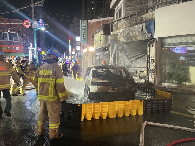 지난 23일 부산 연제구 연산동 한 교차로에서 소방관들이 전기차를 이동식 침수조에 가두고 불길을 잡고 있다. 부산소방재난본부 제공