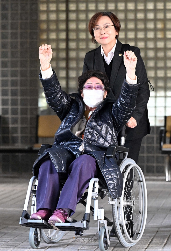 일본군 ‘위안부’ 피해자 이용수 할머니가 23일 서울중앙지법에서 일본을 상대로 제기한 손해배상 청구 소송의 항고심 선고 공판에 출석한 뒤 법원을 나서면서 만세를 하며 기뻐하고 있다. 뒤는 이나영 정의기억연대 이사장. 이날 서울고법 민사합의33부(부장 구회근)는 항소심에서 ‘각하’ 판결한 1심을 취소하고 일본 정부가 이 할머니 등이 청구한 금액을 배상하라고 판결했다. 오장환 기자