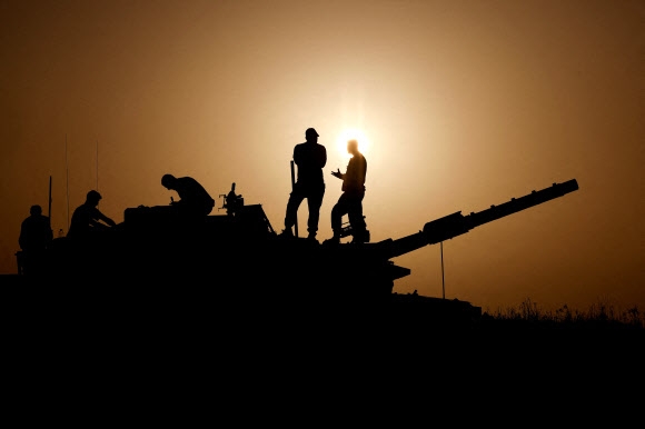 이스라엘 병사들이 하마스와의 나흘 휴전 및 인질 맞석방이 다음날부터 시작한다고 발표한 23일(현지시간) 남부 가자지구와의 국경 근처 탱크 위에서 얘기를 주고받고 있다. 이스라엘 남부 로이터 연합뉴스