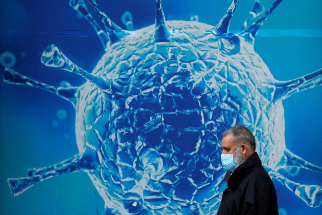 보호용 마스크를 쓴 한 남성이 지역 과학 센터 밖의 바이러스 그림 앞을 지나가고 있는 모습. 서울신문DB