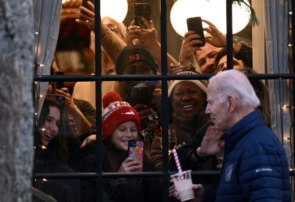 조 바이든 미국 대통령이 추수감사절 연휴를 즐기는 25일(현지시간) 매사추세츠주 낸터킷에서 친척들과 쇼핑을 즐기는데 구경꾼들이 창문 안에서 그를 사진 찍기에 바쁘다. 낸터킷 AFP 연합뉴스