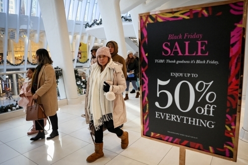 ‘블랙 프라이데이’였던 지난 24일(현지시간) ‘50% 세일’ 이라고 쓰인 미국 뉴욕의 한 쇼핑몰 간판 앞을 고객들이 지나가고 있다. 로이터 연합뉴스