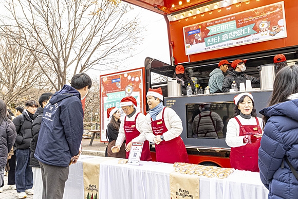 원용걸(가운데 하늘색 목도리) 서울시립대 총장이 산타 바리스타가 돼 학생과 교직원들에게 손수 커피와 쿠키를 나눠주고 있다. 서울시립대학교 제공