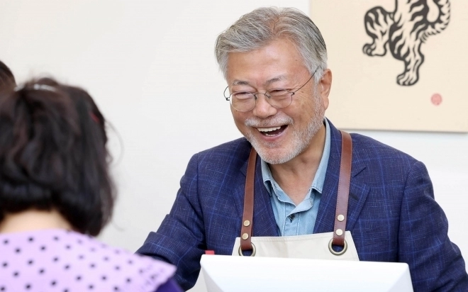문재인 전 대통령이 26일 오후 경남 양산시 하북면 자신의 책방 ‘평산책방’에서 계산 업무를 하며 책을 손님에게 건네고 있다. 2023.4.26 연합뉴스