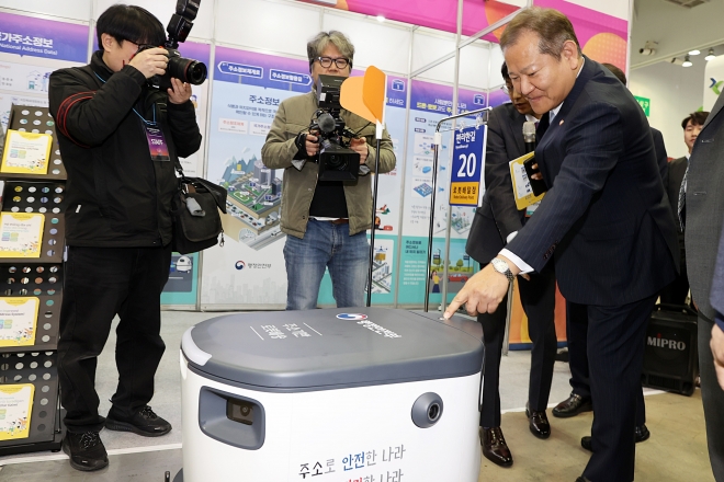 이상민 행안부 장관이 지난달 25일 부산 벡스코에서 열린 대한민국 정부 박람회에서 주소 기반 배달 로봇 ‘뉴비’가 가져온 물건을 받고 있다. 행안부 제공