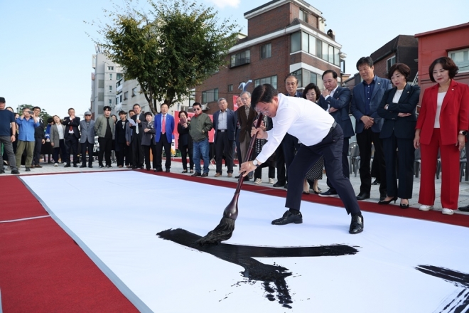박강수 서울 마포구청장이 11일 홍대 레드로드에서 열린 한글멋글씨전 행사에서 대형 붓을 이용해 ‘마포사랑’을 적고 있다. 2023.10.11 마포구 제공