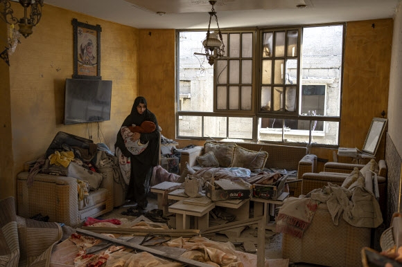 팔레스타인 여성이 지난 9일(현지시간) 가자지구 남쪽 끝 라파의 한 집안에서 이스라엘군의 공습에 모든 것이 엉망이 된 채 아이를 돌보고 있다. 라파 AP 연합뉴스