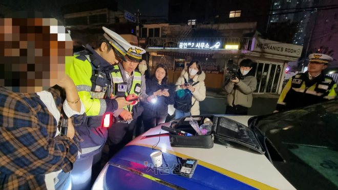 연말 모임이 늘고 있는 가운데 지난 9일 서울 마포구 합정역 인근 도로에서 경찰이 비접촉 감지기에서 알코올 반응이 나온 한 운전자를 상대로 호흡 측정기로 2차 검사를 하고 있다. 김예슬 기자