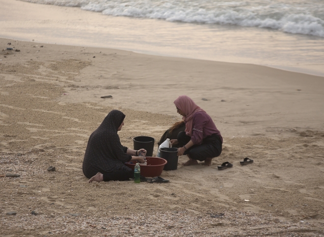 12일(현지시간) 팔레스타인 가자지구 중부 데이르 알발라의 해변에서 주민들이 바닷물로 빨래하고 있다. 2023.12.12 EPA 연합뉴스