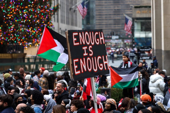 성탄절(현지시간) 미국 뉴욕에서 열린 팔레스타인 지지 집회 참석자들이 ‘그만하면 충분하다’는 격문을 들고 팔레스타인 깃발을 흔들고 있다.  뉴욕 AFP 연합뉴스