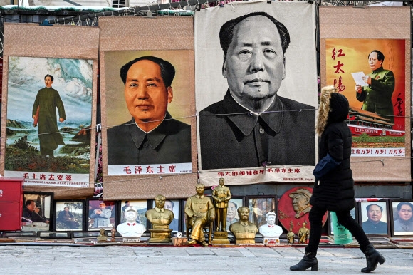한 여성이 마오쩌둥 탄생 130주년을 맞은 26일 그의 초상화 등이 걸린 베이징의 골동품 시장을 걸어가고 있다. 베이징 AFP 연합뉴스