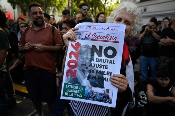 지난 20일(현지시간) 아르헨티나 부에노스아이레스의 마요 광장에서 하비에르 밀레이 대통령의 경제정책에 반대하는 집회에 참석한 여성이 관련 내용을 담은 신문을 들어 보이고 있다. AFP 자료사진 연합뉴스