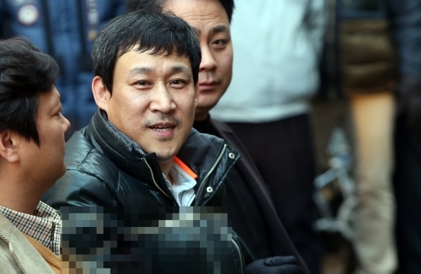 김상훈이 2015년 1월 현장검증 때 가족을 잃은 유족들이 울부짖자 웃고 있다.