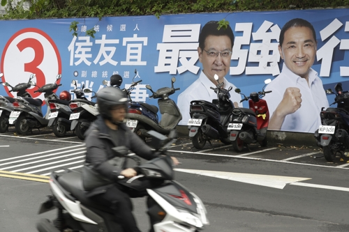 한 대만 시민이 지난 30일 국민당 허우유이(오른쪽) 대선후보의 포스터 앞을 지나고 있다. 타이베이 AP 연합뉴스