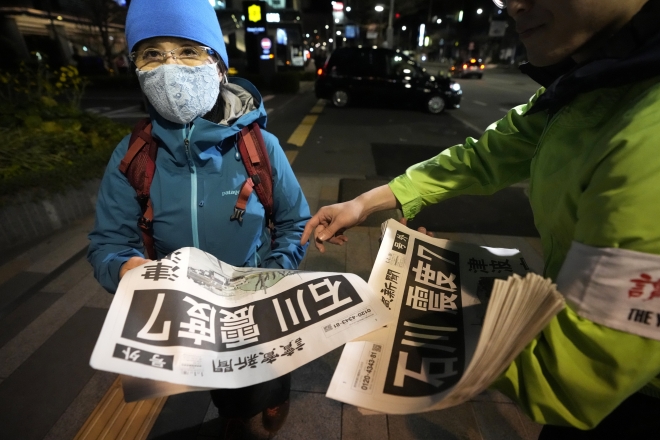 한 일본 시민이 지진 관련 소식이 담긴 요미우리 신문을 받고 있다.  2024.1.1 도쿄 AP 연합뉴스