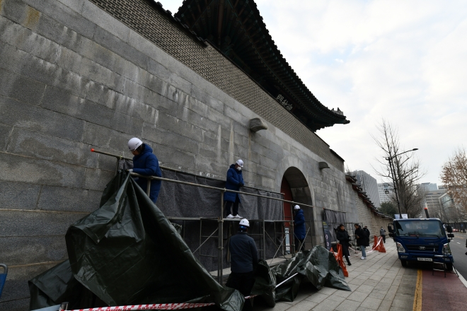 지난달 스프레이로 낙서됐던 흔적을 지운 경복궁 담벼락이 4일 공개됐다. 이날 오전 현장 관계자들이 설치된 가림막을 제거하고 있다. 문화재청 제공