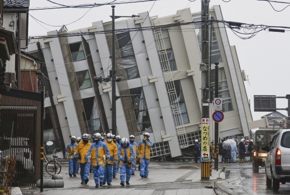 새해 첫날 규모 7.5 강진이 발생한 일본 혼슈 중부 이사카와현의 와지마시에서 4일 소방관들이 지진으로 무너진 건물 근처를 지나고 있다. 2024.1.4 AP 연합뉴스