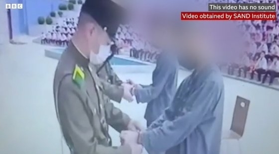 북한 10대 소년 2명이 야외 운동장에서 수갑을 차고 있는 모습. BBC 보도화면 캡처