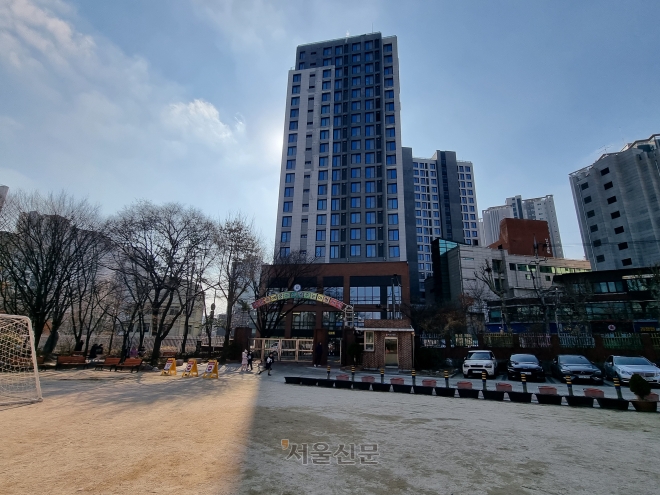 29일 서울 마포구 한 초등학교 정문이 인근 고층 오피스텔 그늘에 잠겨 있다. 김중래 기자