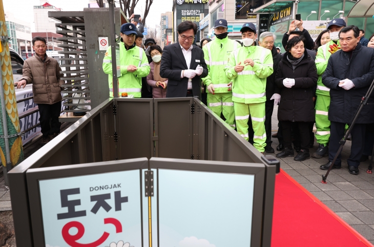 박일하(가운데) 서울 동작구청장 지난 6일 오후 노량진역 인근에서 열린 ‘태양광 자동 접이식 생활폐기물 수거함 시연식’에서 개폐 시연을 하고 있다. 연합뉴스