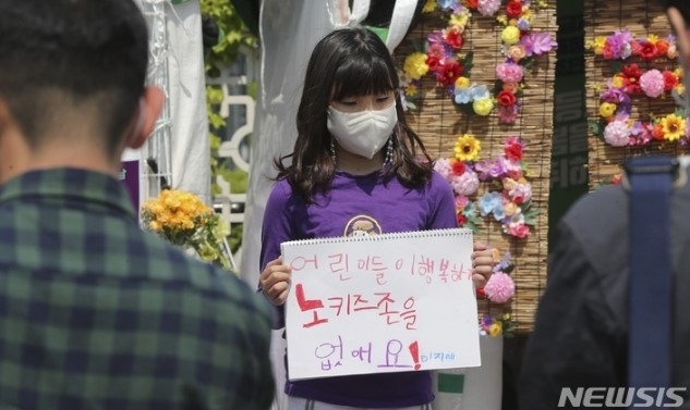 한 어린이가 2022년 5월 서울 영등포 국회 앞에서 열린 ‘어린이날 100주년, 어린이차별철폐의 날 선포 기자회견’에 참석해 노키즈존 반대 문구가 적힌 스케치북을 들고 있다. 뉴시스