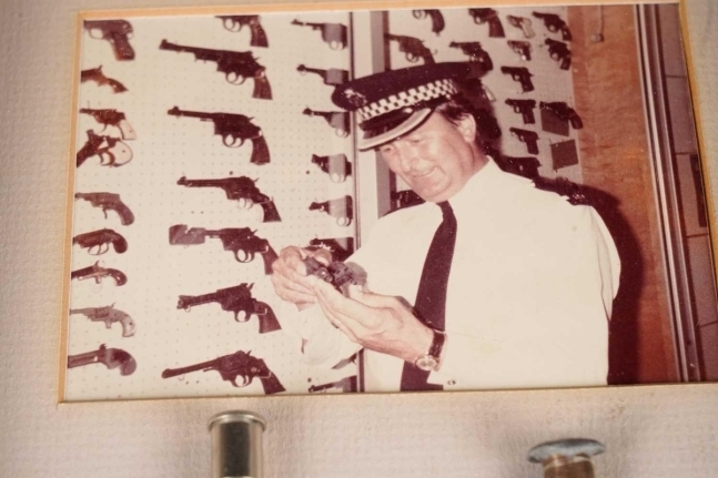암살범의 권총을 들고 있는 브라이언 테일러의 사진. 앤더슨 앤드 갈런드 홈페이지