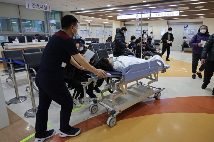 전공의 집단행동이 9일째 이어지고 있는 가운데 27일 서울의 한 대학병원에서 병원 관계자가 환자를 베드에 눕혀 병동에서 이동시키고 있다. 연합뉴스