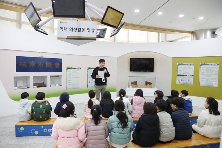 19일 성남시의회를 견학하러 온 당촌초등학교 3학년 학생들이 홍보관에서 견학진행자의 설명을 듣고 있다. 성남시의회 제공