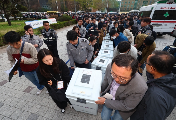 서울 관악구 서울대 종합체육관에 마련된 개표소에 도착한 투표함을 관계자들이 옮기고 있다. 연합뉴스