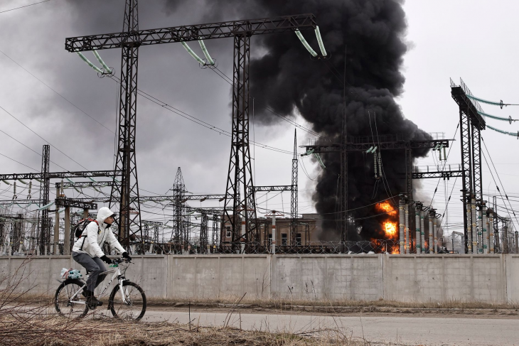 한 우크라이나 시민이 러시아의 공습으로 불타고 있는 전력 시설 앞을 자전거를 타고 지나고 있다. 하르키우 AP 연합뉴스