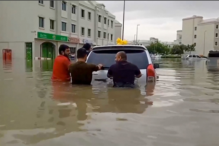 16일(현지시간) 폭우가 쏟아진 두바이에서 남성들이 잠긴 차량을 이동시키고 있다. 2024.4.16 두바이 AFP 연합뉴스