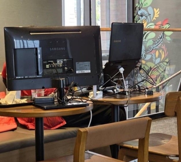 한 프랜차이즈 카페에서 고객이 좌석에 모니터를 설치해 작업을 하고 있는 모습을 촬영한 사진이 화제가 되고 있다. 온라인 커뮤니티 캡처