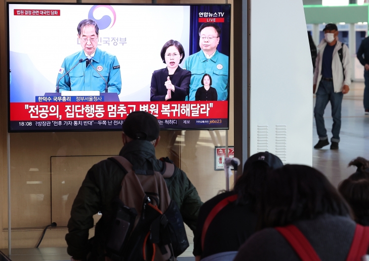 16일 오후 서울 중구 서울역에서 시민들이 한덕수 국무총리의 ‘의대 정원 관련 대국민담화’ 발표 방송을 지켜보고 있다. 연합뉴스