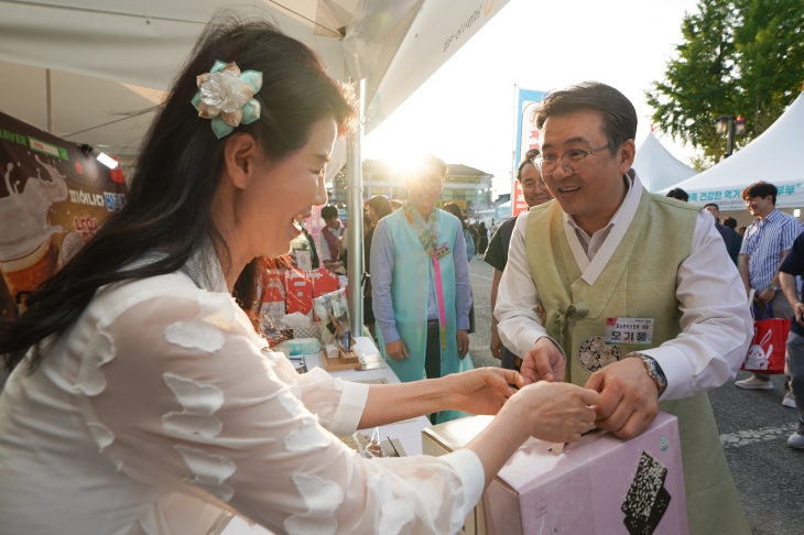 오기웅(오른쪽) 중소벤처기업부 차관이 10일 전북 남원에서 열린 춘향제 행사를 방문해 소상공인 판매부스를 둘러보고 물건을 사고 있다. 중소벤처기업부 제공