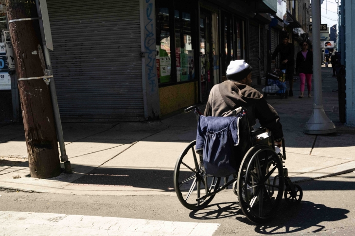 휠체어를 탄 남성이 횡단보도를 건너고 있다. 켄싱턴의 많은 사람들이 마약으로 인해 신체의 일부를 절단했다.