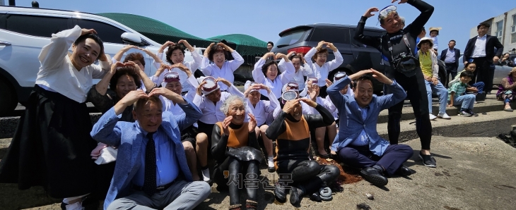 지난달 25일 제주시 한림읍 귀덕2리 포구에서 처음 은퇴식을 한 해녀들과 김성근(앞줄 왼쪽 첫 번째) 귀덕2리어촌계장, 양영철(네 번째) 제주국제자유도시개발센터(JDC) 이사장, 양종훈(맨 오른쪽) 제주해녀문화예술연구협회 이사장이 하트 모양 포즈를 취하고 있다.