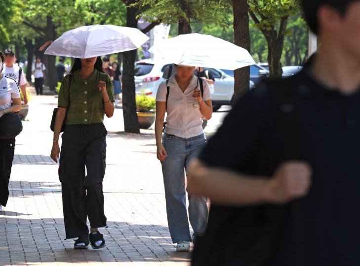 10일 경북 경산시 영남대 정문에서 한 학생이 햇빛을 피하기 위해 셔츠를 머리에 둘러쓴 채 걷고 있다. 이날 경산에는 폭염주의보가 발령됐다. 폭염주의보는 하루 최고체감온도가 33도 이상인 상황이 이틀 이상 지속할 것으로 예상되면 내려진다.  연합뉴스