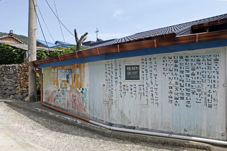 부여 송정그림책마을의 벽화. ‘덤북산에 떠오르는 햇빛 아래서~’로 시작하는 야학당 교가와 야학당 풍경이 그려졌다.