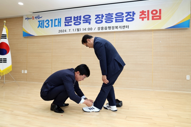 김성 군수가 문병욱 장흥읍장에게 운동화를 선물하며 직접 신발끈을 묶어주고 있다.