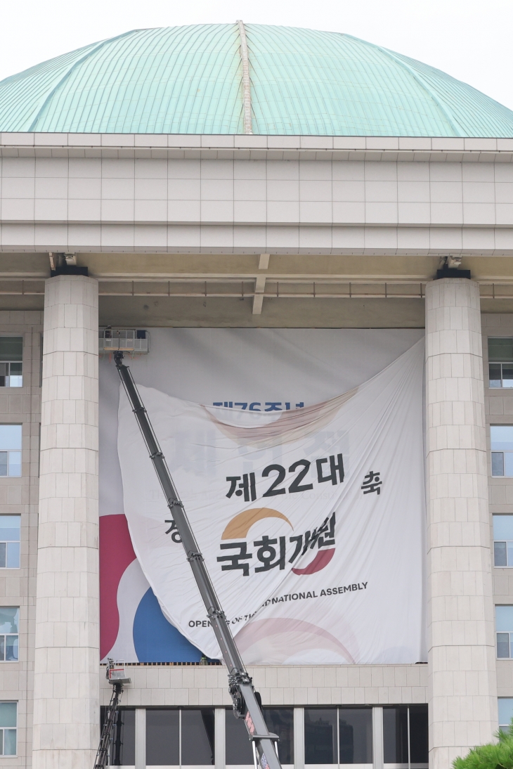 서울 여의도 국회의사당 본관에 설치된 제22대 국회 개원 축하 현수막이 7일 오후 철거되고 있다. 지난 5일 열릴 예정됐던 22대 국회 개원식은 ‘채상병특검법’을 둘러싼 여야 충돌의 여파로 무기한 연기됐다. 연합뉴스