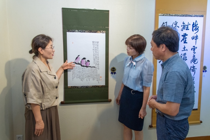 ‘제10회 전국 섬진강 미술대전’에서 대상을 수상한 홍은주 캘리그라피 재능봉사단원이 전시회를 방문한 관람객들에게 자신의 작품을 설명하고 있다.