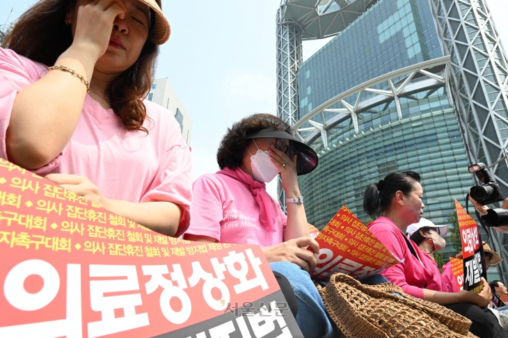 한국환자단체연합회, 한국유방암환우총연합회, 한국희귀·난치성질환연합회 등 환자 단체 회원들이 4일 서울 종로구 보신각 앞에서 의사 집단휴진 철회와 재발방지법 제정을 촉구하는 가운데 참가자들이 코넬리아드랑게 증후군 환자의 어머니인 김정애 씨의 발언을 들으며 눈물을 흘리고 있다. 2024.7.4 홍윤기 기자