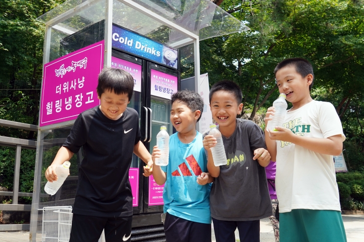 서울 동대문구가 운영 중인 ‘힐링 냉장고’에 든 생수를 한 병씩 받은 어린이들이 더위를 식히며 즐거워하고 있다. 동대문구 제공