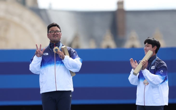 김우진(왼쪽)이 4일(한국시간) 프랑스 파리 레쟁발리드에서 열린 2024 파리올림픽 양궁 남자 개인전 결승에서 금메달을 획득한 뒤 시상식 시상대에서 손가락 세 개를 펴 보이는 세리머니를 하고 있다. 오른쪽은 남자 개인전 4강에서 플로리안 운루(독일)를 꺾고 동메달을 획득한 이우석. 파리 연합뉴스