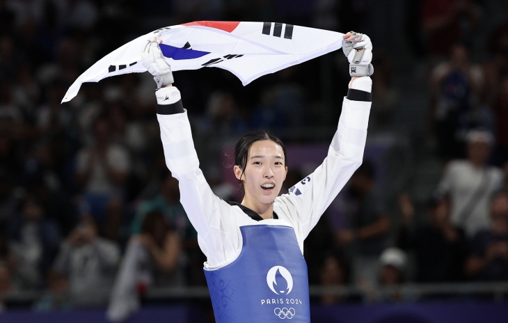 한국 태권도 국가대표 김유진이 9일(한국시간) 프랑스 파리 그랑팔레에서 열린 파리올림픽 태권도 여자 57㎏급 결승에서 나히드 키야니찬데(이란)를 2-0으로 이긴 뒤 태극기를 휘날리고 있다. 파리올림픽사진공동취재단