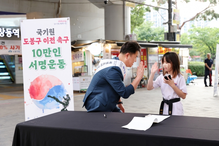 오언석(왼쪽) 서울 도봉구청장이 지난 13일 국기원 도봉구 이전 촉구를 위한 창동역 방문에서 만난 어린이와 하이파이브하고 있다. 도봉구 제공